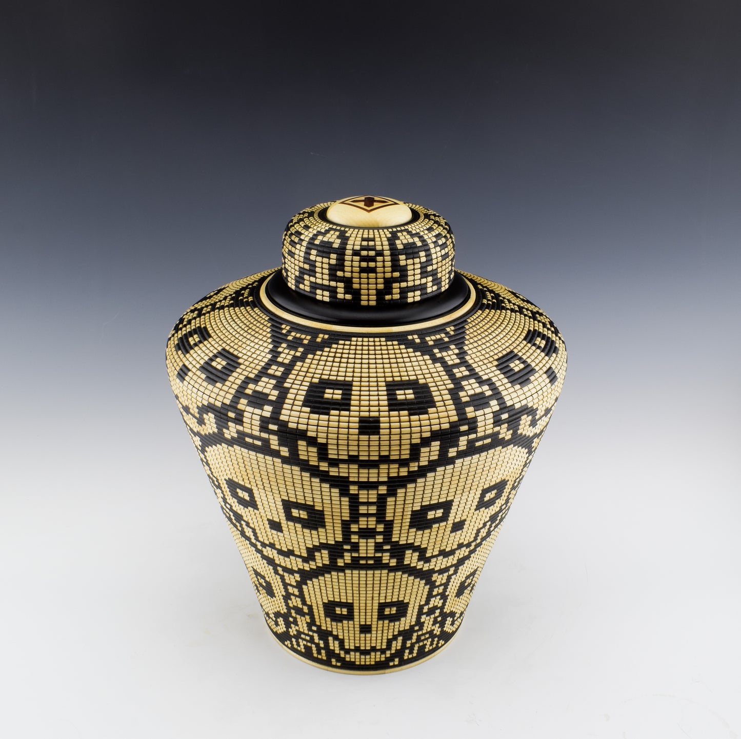 Basket illusion vase with a threaded lid by Simon Roy. Features stacked skulls. made of Maple and india ink. Handmade in Canada.